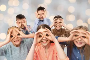Six children with their hands over their eyes in a heart shape formation