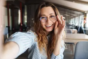 A woman in a striped shirt is smiling and posing for a selfie in a restaurant.
