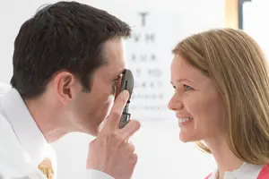 A man holding a device and examining a woman's eye
