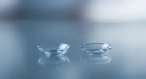 Two clear glass contact lenses sitting on a table