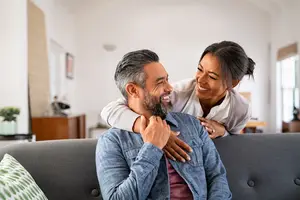 A man and woman sitting on a couch and smiling for a photo.