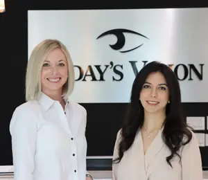 Two women are standing in front of a sign that says Day's Vision