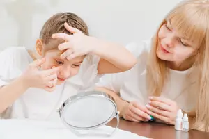 a girl is putting on eye drops while sitting next to a woman who is smiling