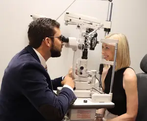eye doctor giving eye exam to smiling blonde patient