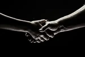 Two hands clasped together with a black background