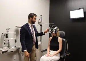 male eye doctor performing eye exam on blonde female patient