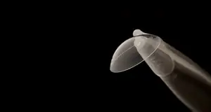 A clear plastic contact lens in a small white plastic container with a curved tip