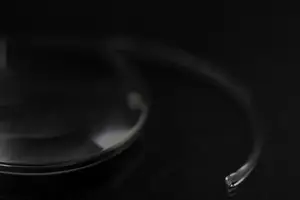 Close-up of a sleek, reflective object resembling a glass lens with a metallic frame on a dark background