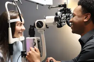 male optician performing eye exam on young female patient