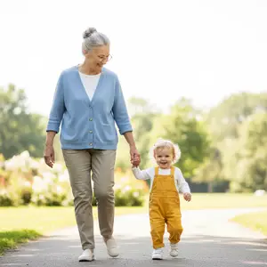 An older woman and a toddler are walking down a sidewalk in a park together.