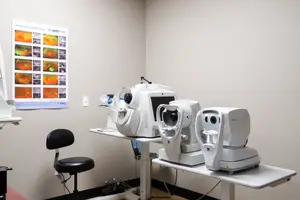 A medical room with an optometrist chair and several medical machines on the table