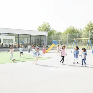 A group of children playing on an outdoor playground with a building and trees in the background.