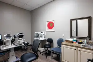Interior of an optometrist's office with medical equipment, chairs, and a sink.