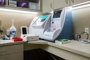 Medical equipment and supplies are organized on a counter in a lab, with a blue and white machine prominently displayed.