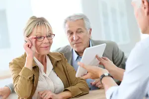 Three elderly people sitting at a table and talking with each other
