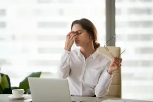 A woman sitting in an office chair rubbing her temples