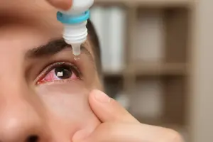 A man applying eye drops to his eye