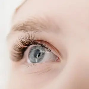Close up of a woman's eye with brown lashes and blue iris