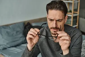 Man adjusting glasses with a serious look on his face