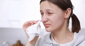 woman wiping her nose with a tissue