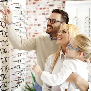 A man, a woman, and a child are inside a store, looking at glasses on display.