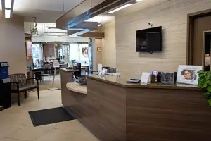An interior of a dental clinic with a reception desk and a television mounted on the wall.