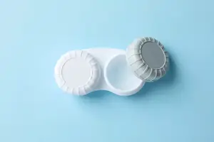 A pair of contact lens cases with white lenses on a blue background