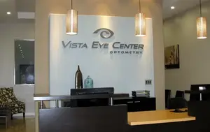 A reception area with a desk, chairs, and lamps at Vista Eye Center Optometry.