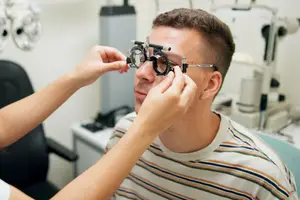 A man in a striped shirt is getting an eye exam from a doctor in a medical clinic.