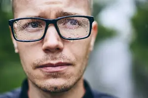 Close up of a man with glasses covered in raindrops