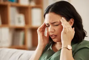 Woman experiencing a headache at home