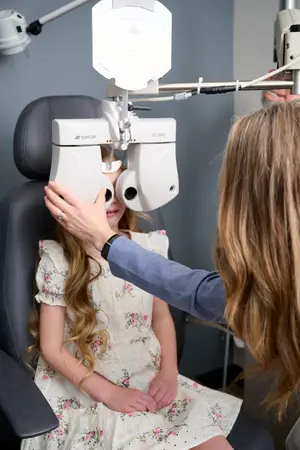 A girl is having her eyes examined by a doctor using a Topcon CV1000 machine.