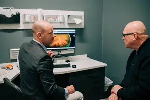 Two men in a medical office talking about an image on a computer monitor