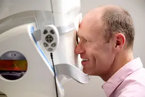 A man is looking into a device with a light on the screen