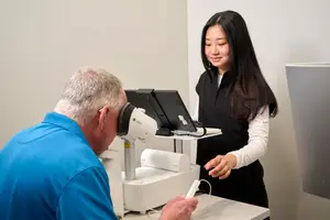 A man wearing a VR headset being assisted by a woman in a medical setting.