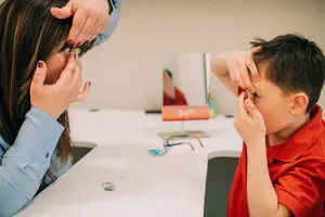 A woman and a boy are looking at each other in front of a mirror