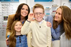 Four people including a boy and a girl are standing close to each other in a store with a smiling face