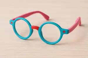 A pair of pink and blue colored glasses with red dots on the sides on a wooden surface