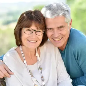 An elderly couple sitting close to each other with smiling faces