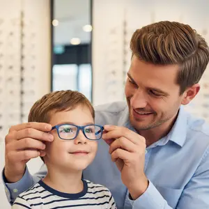 A man in a blue shirt is helping a young boy put on his blue glasses
