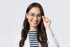 Young woman adjusting glasses and smiling
