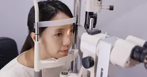 A woman is having her eyes examined by an ophthalmologist using an ophthalmoscope