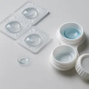 The image displays a close-up view of a set of clear contact lenses and their storage containers on a white background.