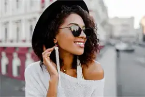 A woman smiling and posing for a photo with sunglasses on
