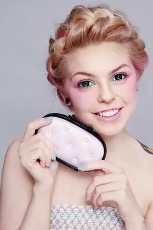 A woman is holding a pink brush in her hands and is smiling.