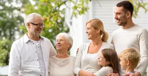 A family is standing in front of a house, smiling, and looking happy.