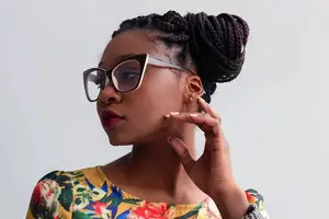 A woman with glasses and a floral shirt poses for a photo.