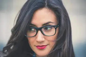 A woman with black hair and glasses smiling for a photo