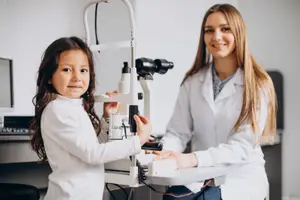 Girl having her eyes checked by a woman in a lab coat at an optometrist's office