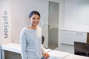 woman standing at a reception desk smiling at the camera